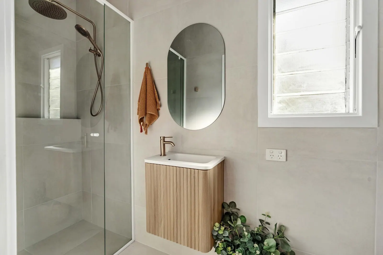 Detail of a renovated bathroom with brass shower and fluted vanity