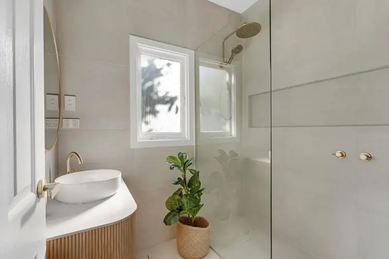 Bathroom renovation with fluted timber vanity, brass tapware and frameless shower