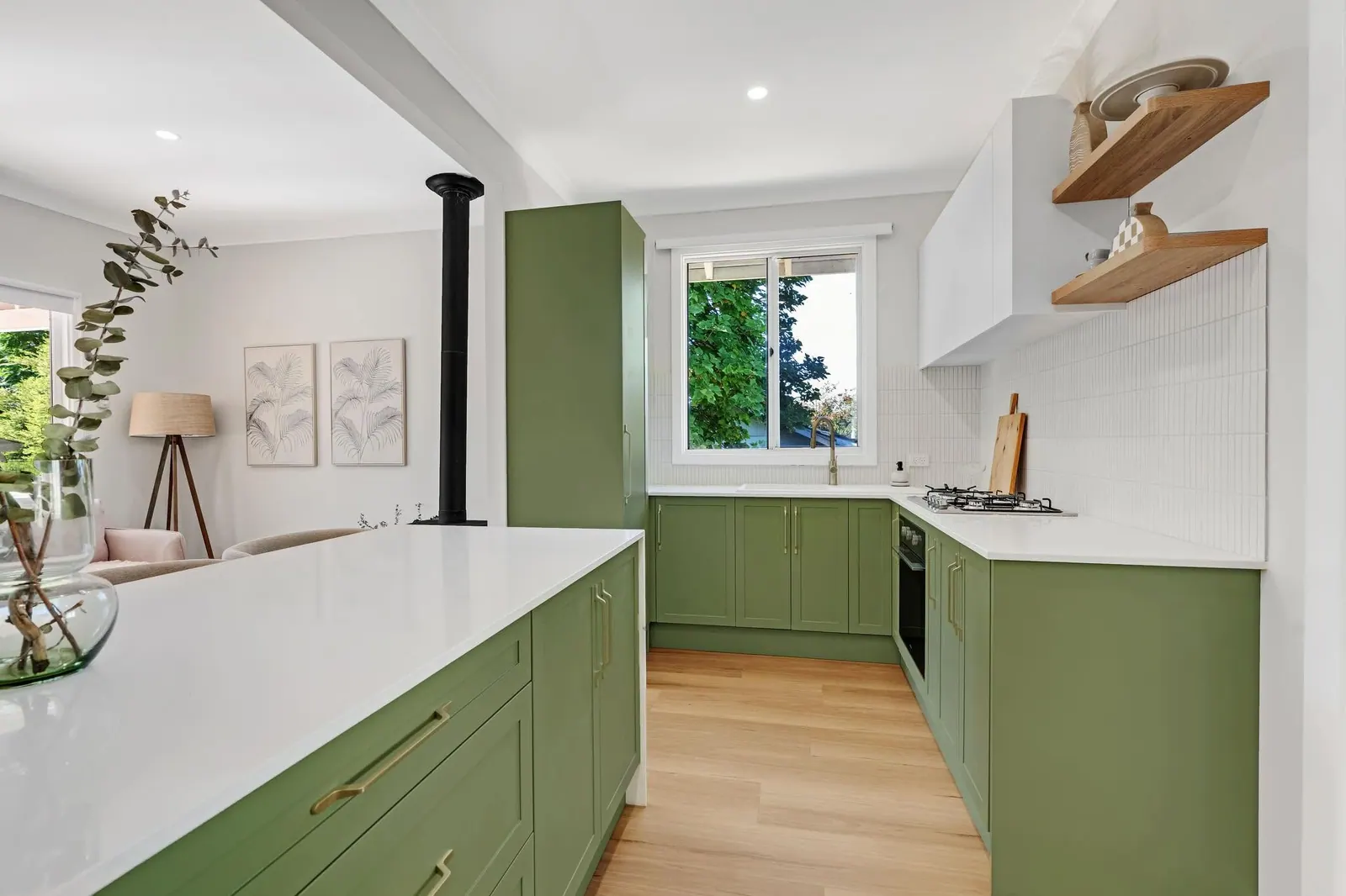Kitchen renovation with sage green cabinetry, brass handles and stone benchtops